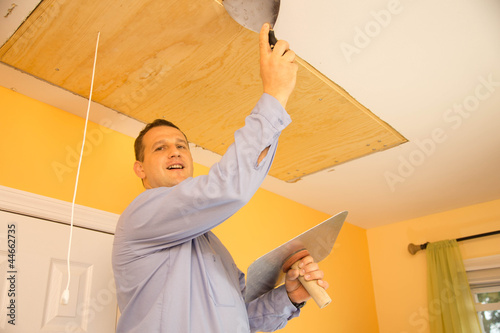 Handyman in uniform spackling ceiling