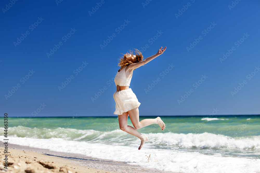 Young redhead girl jumping at the beach. Young redhead girl jumping at the beach.
