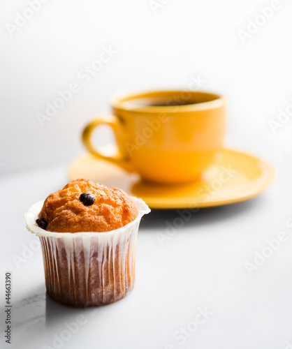 .Coffee in an yellow cup and a muffin