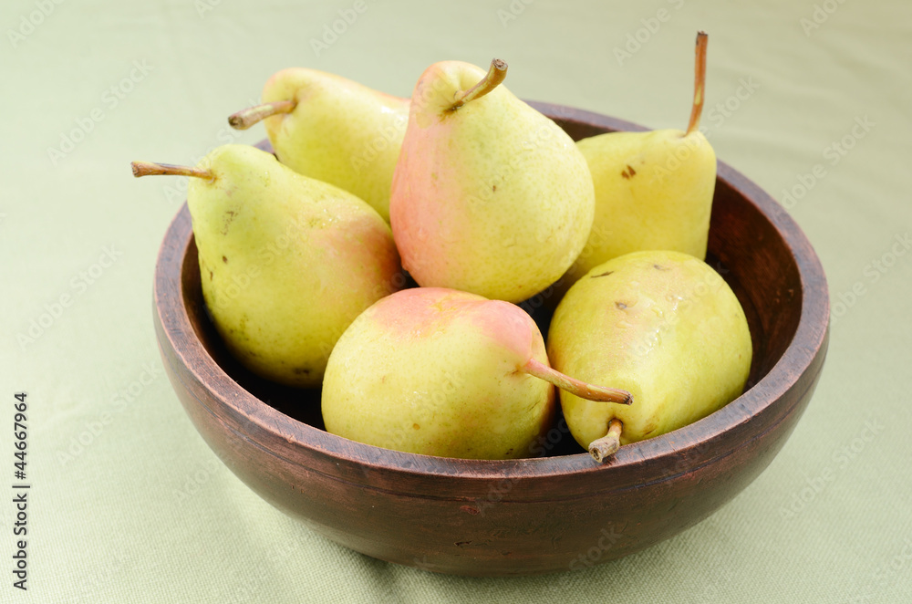 Yellow pears in old wooden bowl on light-green background Yellow pears in old wooden bowl on light-green background