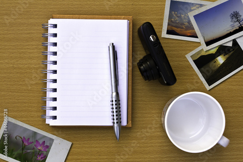 Note book , photo , pen and camera. On the floor of the wooden t photo