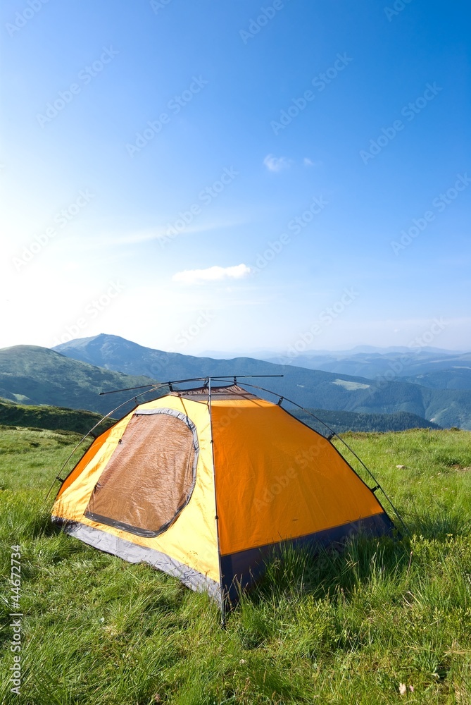 orange touristic tent in a mountain prairie