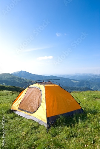 orange touristic tent in a mountain prairie