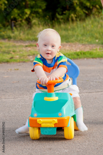smiling baby boy with Down syndrome who driving toy car