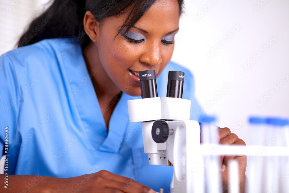 Fototapeta premium Young scientific woman using a microscope