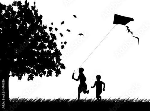 Silhouette of running boys with flying kite in autumn or fall