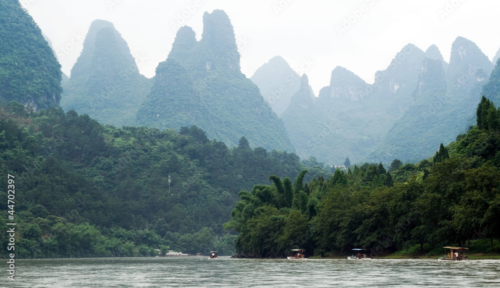 Traveling people through valley of Li River between Yangshuo