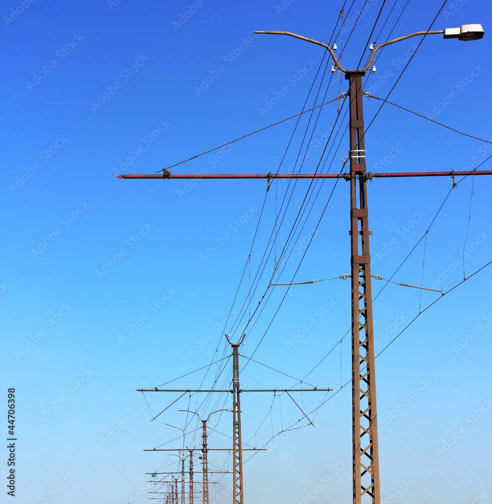 Railroad railway catenary lines against clear blue sky.