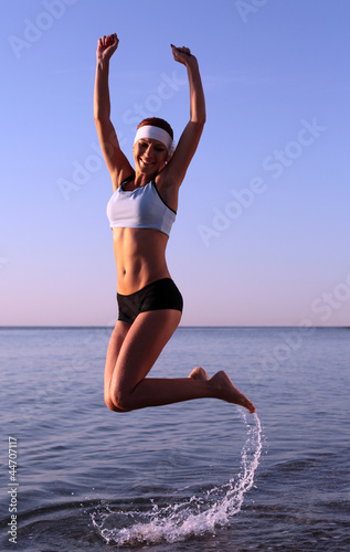 Happy young woman is jumping in the beach
