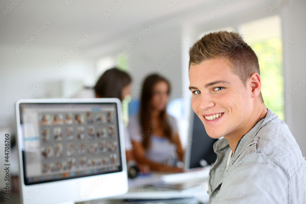 Naklejka premium Young man sitting in office in front of desktop computer