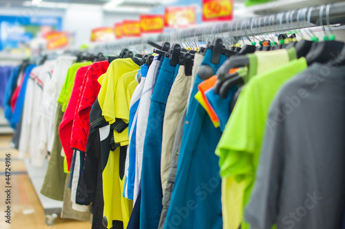 Color T-shirts and sport trousers on stands in supermarket