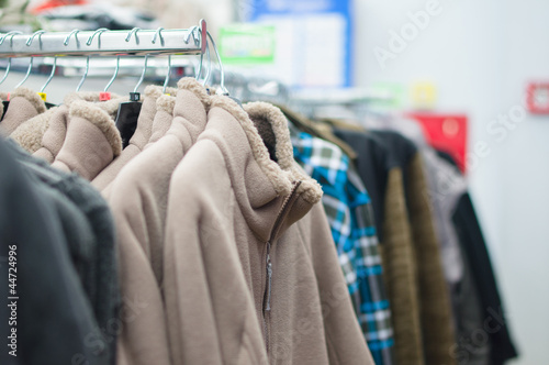 Variety of sweaters and vests on stands in supermarket