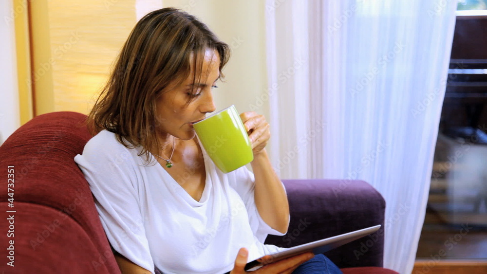 Beautiful woman at home drinking tea reading iPad tablet