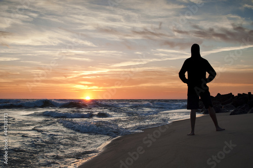 Man standing looking at the sunset in the beach