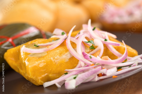 Peruvian tamale made of corn and chicken with salsa criolla