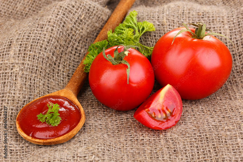 Ketchup and ripe tomatoes on sacking close-up Ketchup and ripe tomatoes on sacking close-up