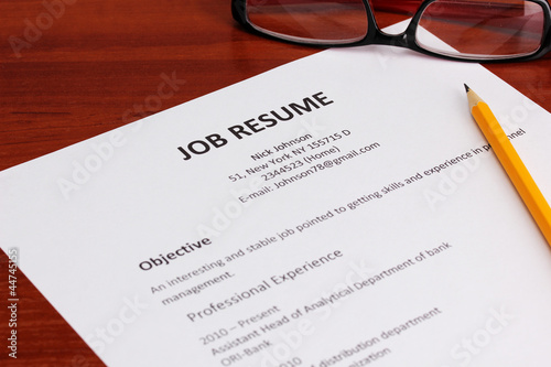 Closeup of resume with pencil and glasses on wooden table