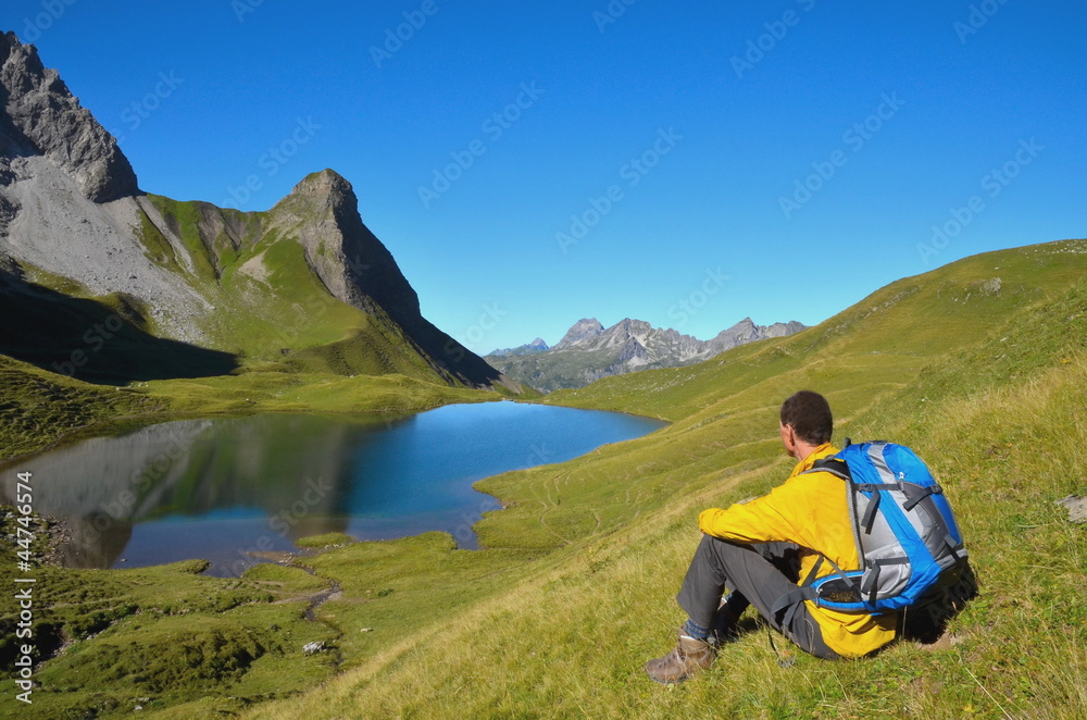 Wanderer rastet mit Blick auf Bergsee