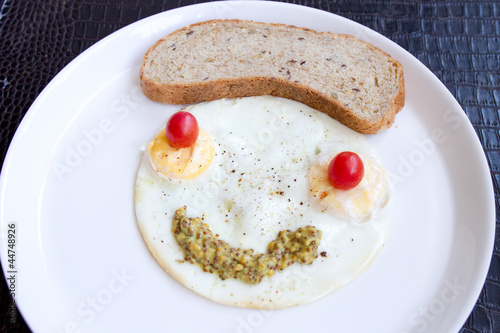 Smiley face from fried eggs with cherry tomatoes