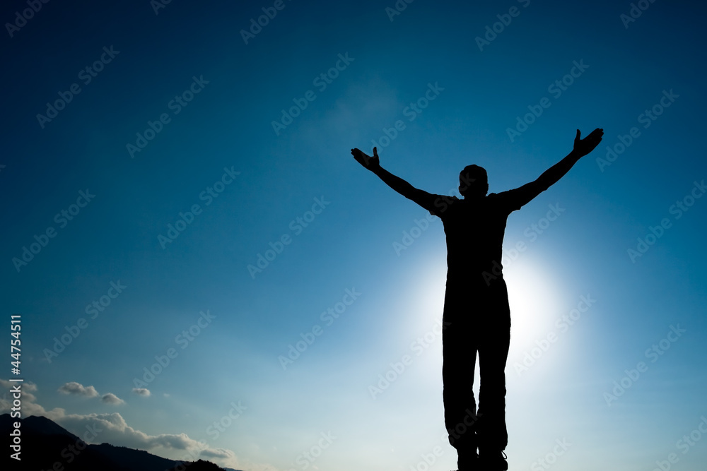 Silhouette of climbing young adult at the top of summit