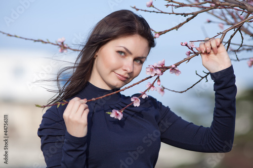 Konstfotografi Girl posing with blossoming peach-tree looking at camera smiling