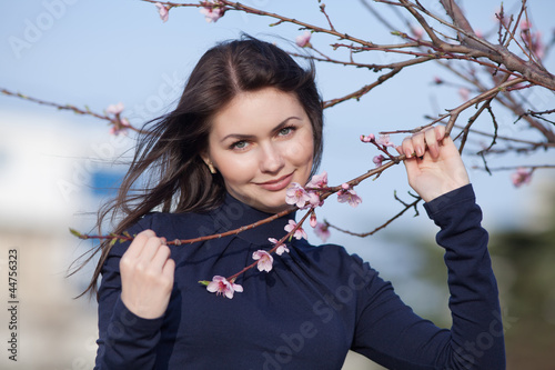 Konstfotografi Girl posing with blossoming peach-tree looking at camera smiling