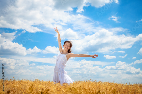 Woman in wheat field with arms outstretched