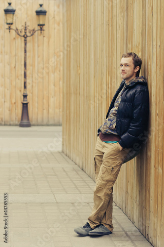 Young man leaning on fence