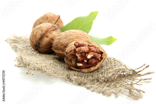 walnuts with green leaves on burlap, isolated on white