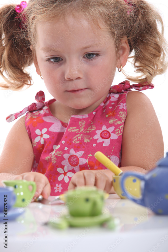 Young girl playing with her tea set Young girl playing with her tea set