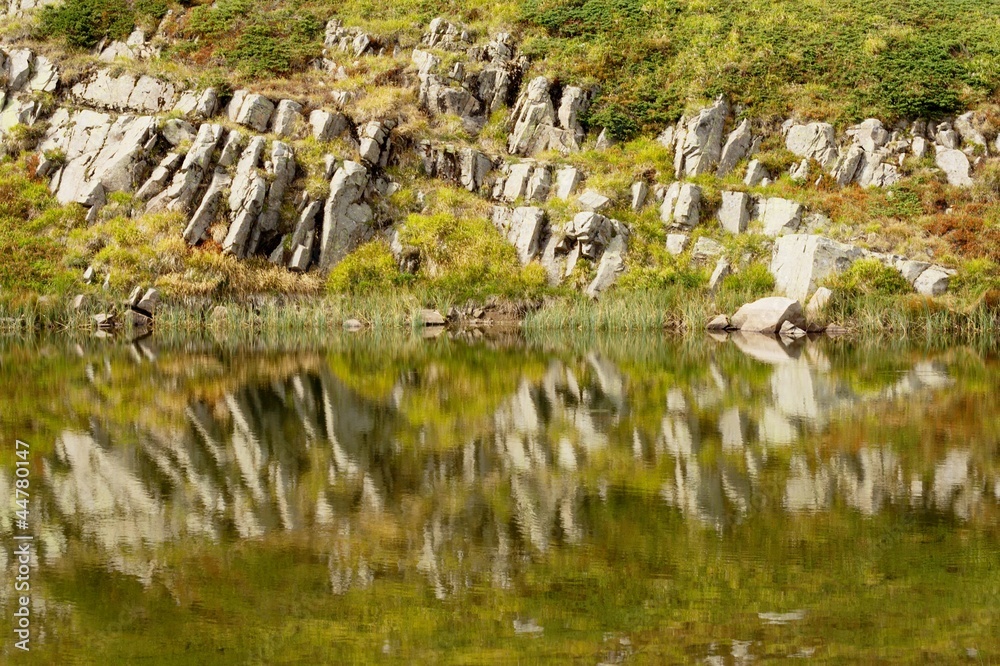 rocks reflection on a mountain lake surface. rocks reflection on a mountain lake surface.