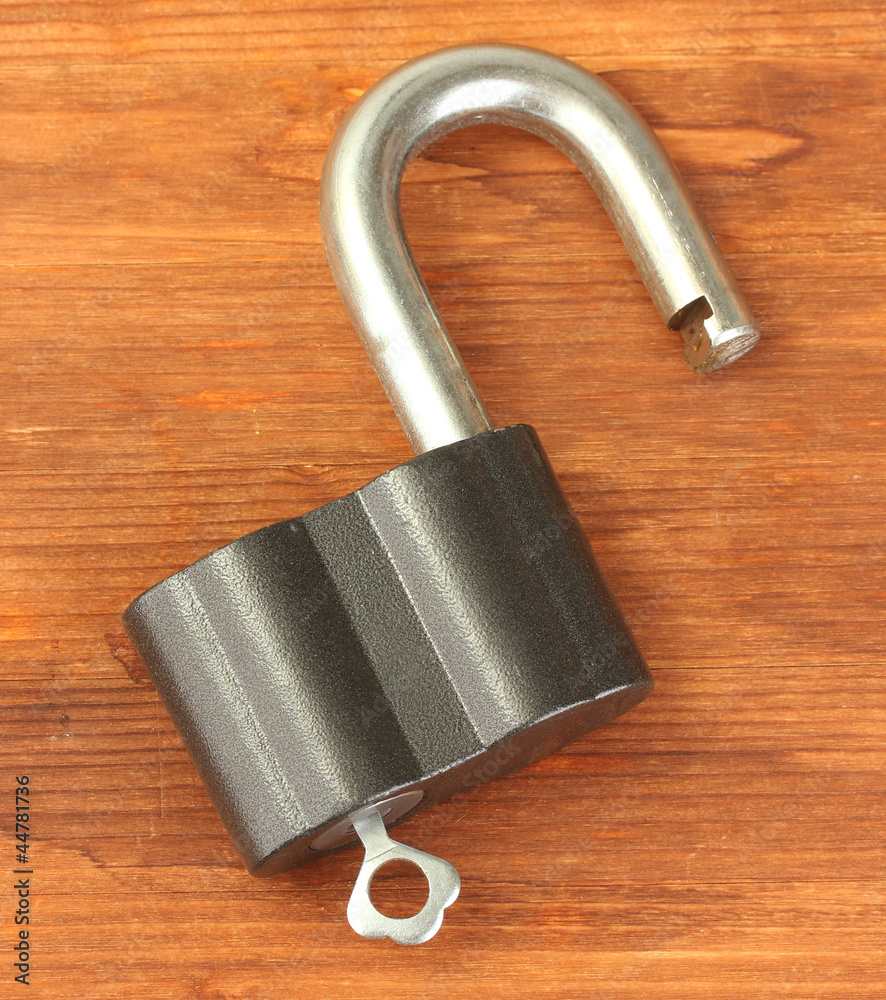 old padlock with key on wooden background close-up old padlock with key on wooden background close-up