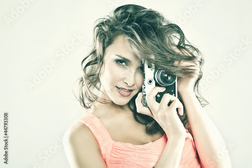 Young brunette woman taking a photo with a retro camera