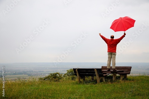 Man with red umbrella is happy in an autumnal landscape