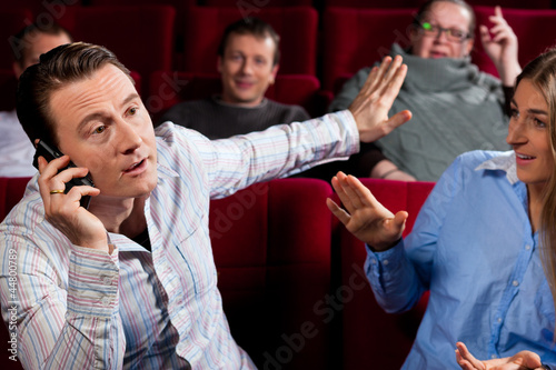 people in cinema theater with mobile phone