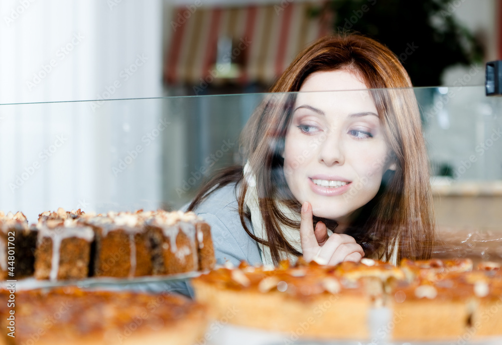 Woman in scarf looking at the bakery showcase full of pies
