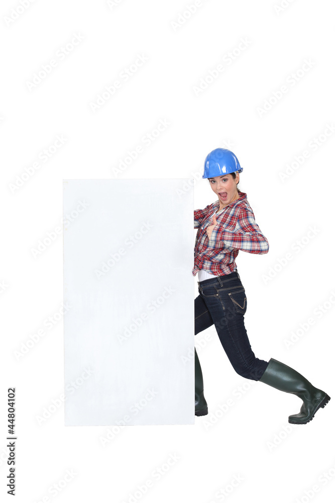 A female construction worker by a billboard.