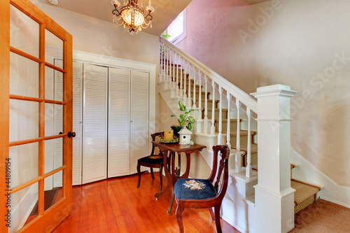 Hallway with white staircase and hardwood floor.