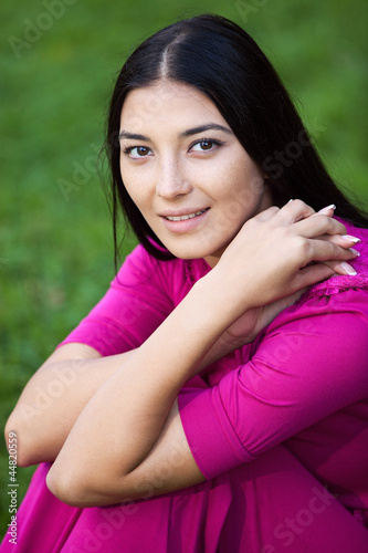 Portrait of a beautiful young woman sitting on the grass