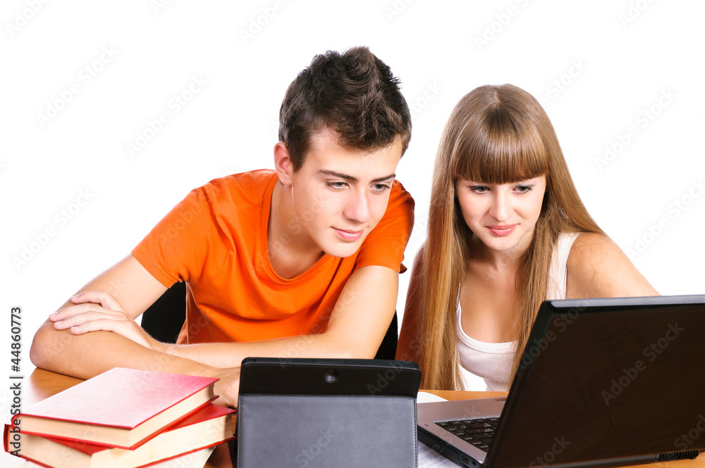 Two students learning with books and laptop sitting at table iso Two students learning with books and laptop sitting at table iso