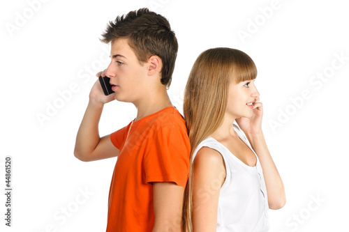 teenage boy and girl chatting on cell phones standing back to ea