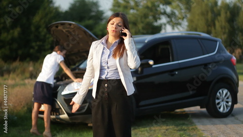 Two young businesswomen next to broken car