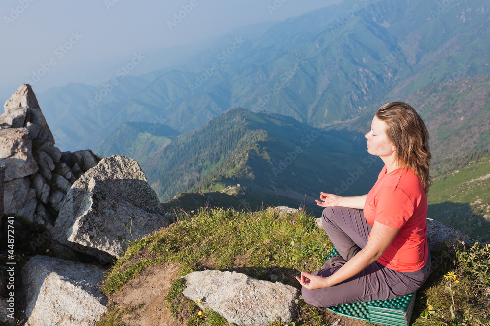 Naklejka premium Young girl doing yoga on top.