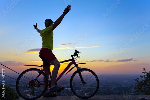 young man with a bicycle at sunset.