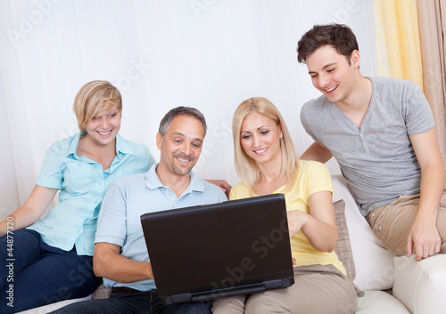 Family together sitting on the couch with laptop