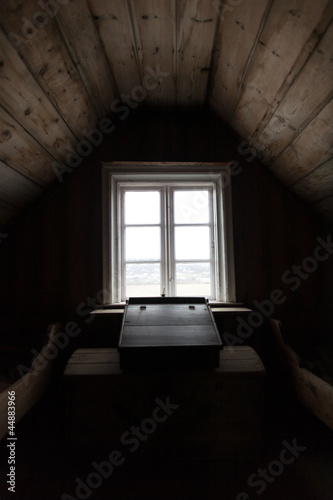 Dark wooden attic room with desk by window