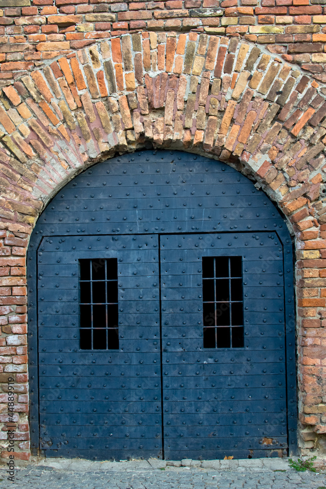 An old iron door in an old brick fortress wall