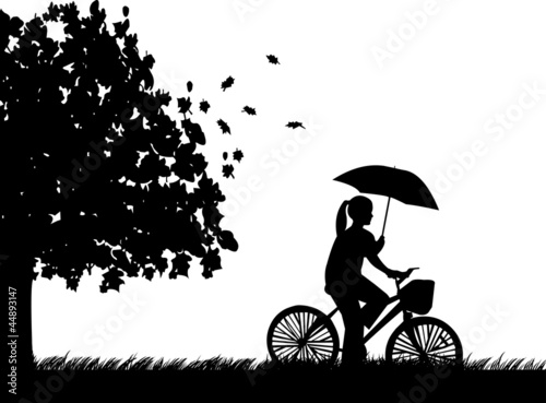 Young woman ride bike in the rain under umbrella silhouette