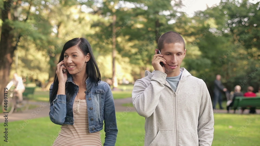 Young couple talking on cellphone in the park Young couple talking on cellphone in the park