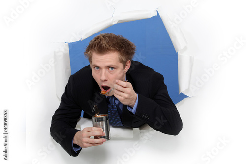 Businessman eating beans from a tin